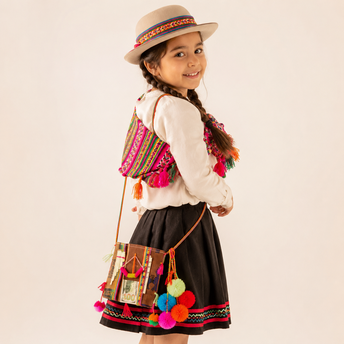Niña usando morral nortino infantil con pompón multicolor vista frontal